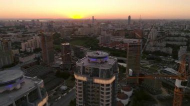 Parti 'nin gökdelenin çatısındaki hava görüntüsü. Akşam sıcak yaz şehri gün batımında. İnşaat alanı, binalar ve kule vinçlerinin yanında.
