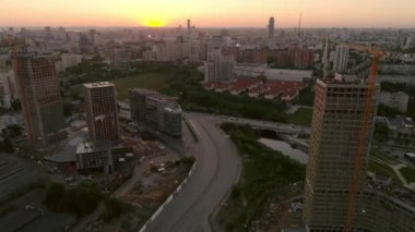 Günbatımında Summer City 'nin hava aracı görüntüsü. Bazı evler inşa edildi, bir ev hala yapım aşamasında. Arabalar yolda gider..