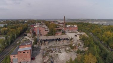 Eski fabrikanın havadan görünüşü. Kırmızı tuğla binalar ve baca. Tesisin her iki tarafında bir demiryolu var. Fabrikanın yakınında büyük bir taş ocağı var. Sonbahar güneşli bir gün