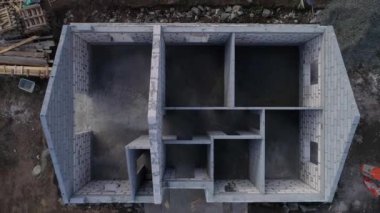 İnşaat alanının yukarıdan aşağıya doğru görüntüsü. Bir köpük bloklama evinin nasıl inşa edildiğini görebilirsiniz. Evin henüz tavanı ya da çatısı yok. İnsansız hava aracı kalkıyor.