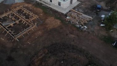 İnşaat alanının havadan görüntüsü. Evlerin nasıl inşa edildiğini görebilirsiniz. İnsansız hava aracı neredeyse bitmiş olan evin, çatısız evin ve duvarların üzerinde uçuyor. İnşaat alanının yanında bir orman var.