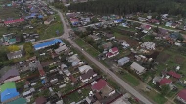 Kırsal bir köyde sonbaharın başlarında, hava manzaralı. Köyde sebze bahçeleri ve asfalt yolları olan evler var. Ormanın yakınında. Ağaçlardaki yapraklar sararmaya başlıyor. Kötü bir gün.