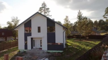 Güzel bir mahalledeki yeni, modern bir ev kulübesinin insansız hava aracı çekimi. Yumuşak fayanslardan yapılmış çatı. Ağaçlar ve çimenler toprakta yetişir.