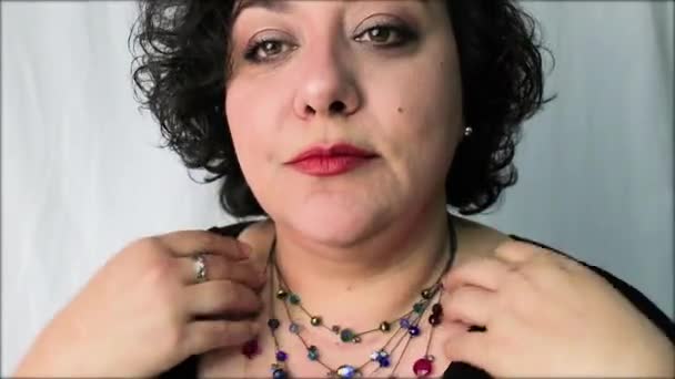 Зрелая женщина кладет ожерелье и смотрит на волосы — стоковое видео