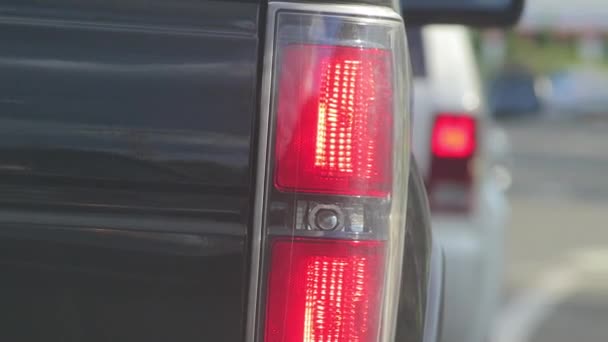 Fechar as luzes da cauda de um veicle em uma luz de parada — Vídeo de Stock