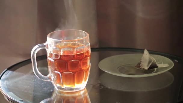 Steaping tea bag on a glass table — Stock Video