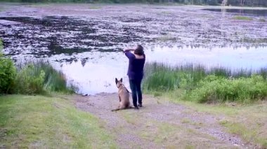 bir gölün yanında bir köpekle kadın