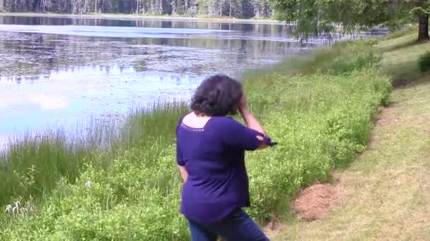 Jovem mulher à beira de um lago — Vídeo de Stock