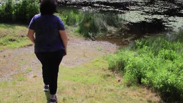 Femme marchant le long d'un lac — Video