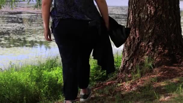 Ragazza si siede sotto l'albero vicino al lago — Video Stock