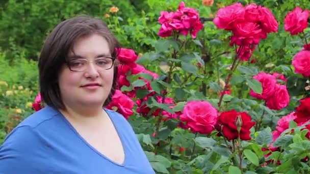 Mujer joven frente a un rosal — Vídeos de Stock