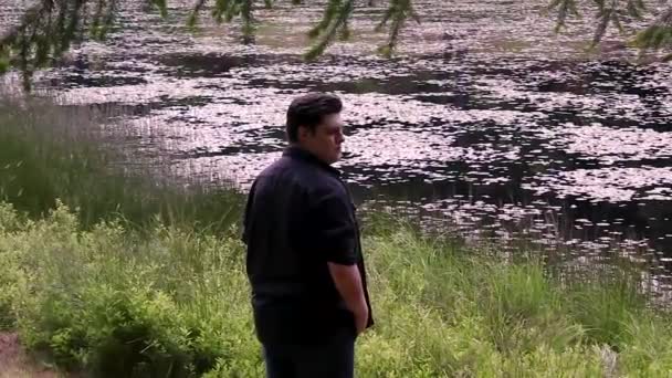 Jeune adulte regarde autour d'un lac — Video