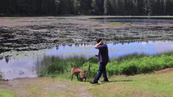Młody mężczyzna z psem nad jeziorem — Wideo stockowe