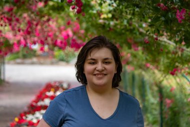 Kemerli bir gül bahçesinde gülümseyen bir kadın