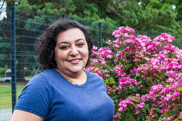 Mujer delante de rosas rosadas — Foto de Stock