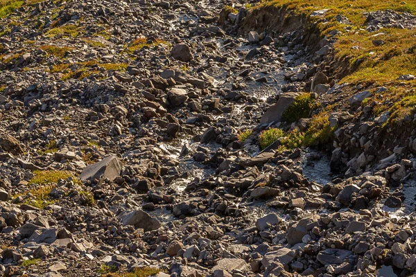 Terreno rocoso de montaña con hierba y un arroyo — Foto de Stock