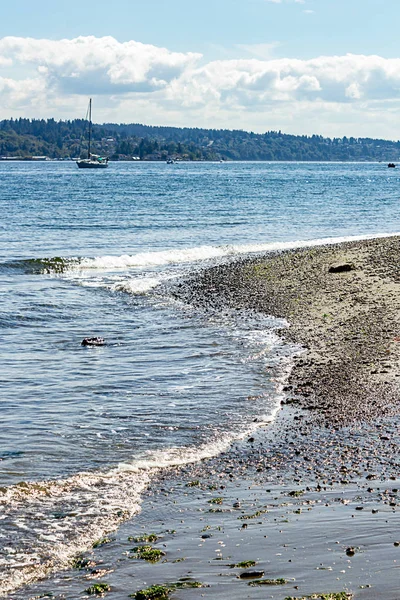 Vagues blanches dorées coulant sur un rivage de gravier — Photo