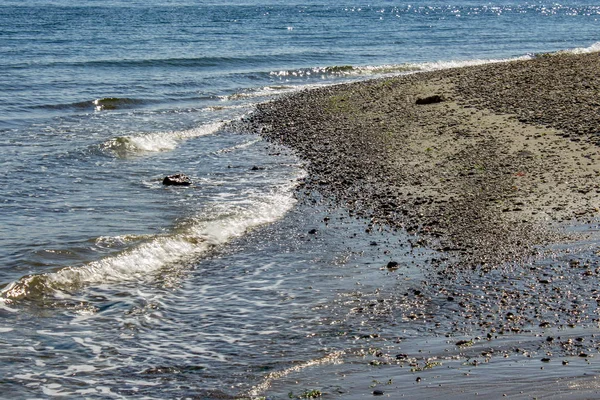 Onde blu dell'oceano che scorrono su una riva rocciosa di ghiaia — Foto Stock