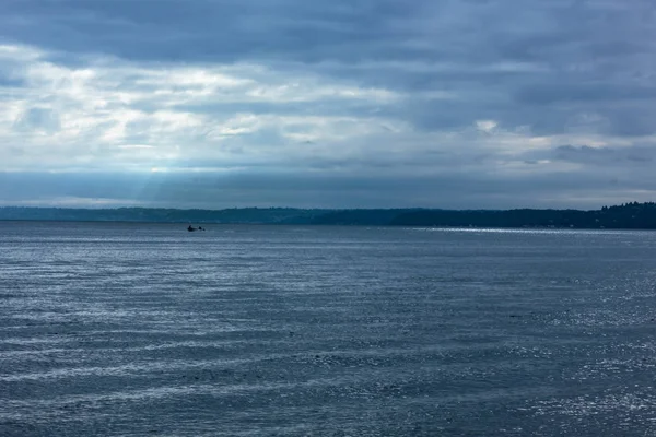 Fasci di luce cadono dalla copertura nuvola sulla barca da pesca — Foto Stock