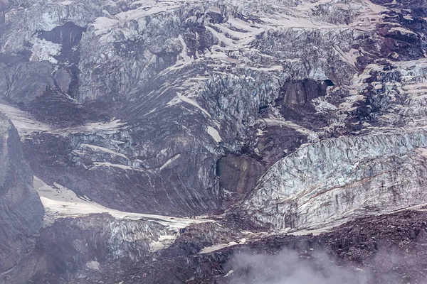 glaciers and harsh mountain side at high altitude with fog and clouds