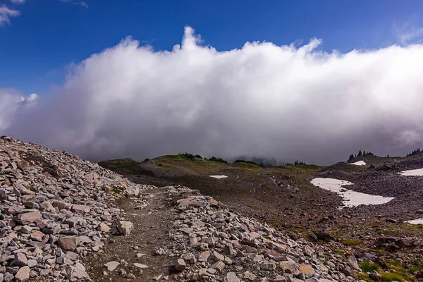 Wolken boven de besneeuwde berg en berg trail — Stockfoto