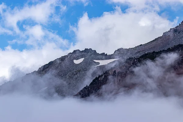 Dura cima rocciosa con nuvole e nebbia — Foto Stock