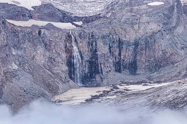 Glaciala snö fält smälta in vattenfall på bergssidan — Stockfoto