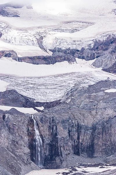 Tall waterfall over harsh landscape of stone and glaciers — Stock Photo, Image