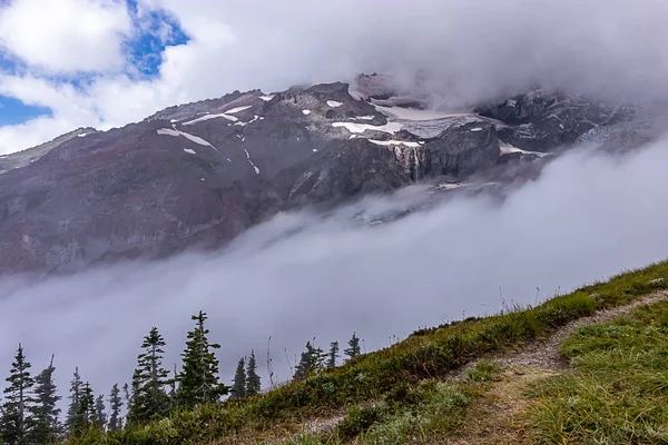 Chmury i mountain top z śniegu i łąka i drzewa poniżej — Zdjęcie stockowe