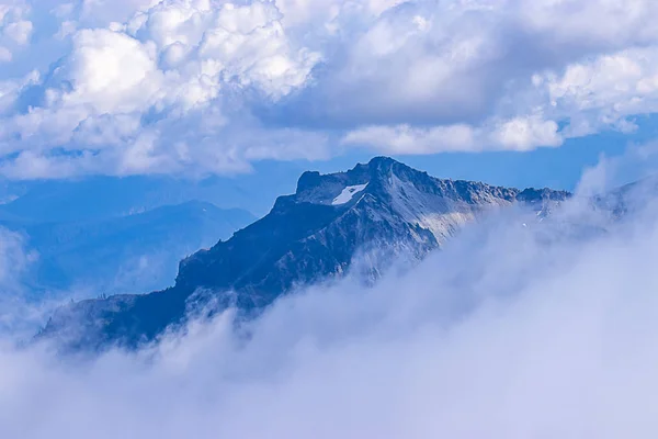 Belo pico de montanha alta com camadas de nuvens — Fotografia de Stock