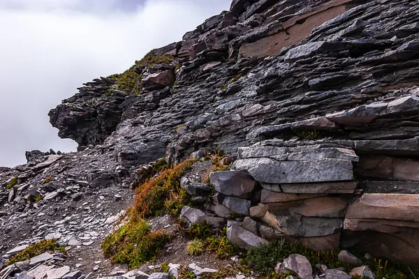 Dentadas rocas musgosas de la ladera de la montaña con nubes —  Fotos de Stock