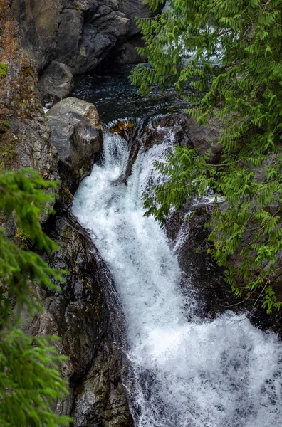 Sauberes, helles Wasser von Wasserfällen, die sich durch dunklen Fels und Schatten bewegen — Stockfoto