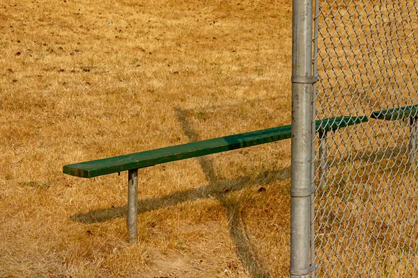 Green bench on edge of summer ball field — Stock Photo, Image