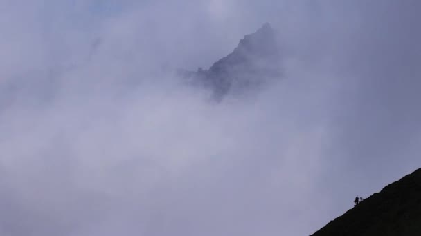 Sommet de la montagne à travers d'épais nuages blancs — Video