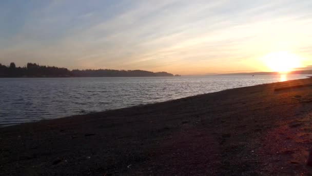 Rocky shoreline at dusk under bright sunset — Stock Video