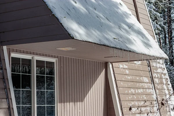Jégcsapok, a tetőre, az épület télen — Stock Fotó