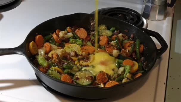 Яйца помешиваются в блюдо из бекона и овощей — стоковое видео