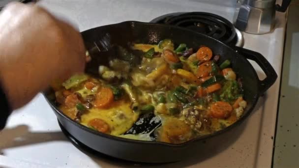 Женская рука перемешивает яйцо и овощную смесь в чугуне — стоковое видео