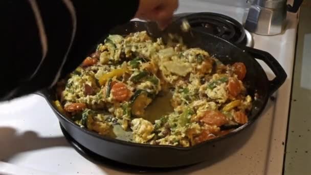 Hand mit Spachtel mischt Frühstück in gusseiserner Pfanne auf — Stockvideo