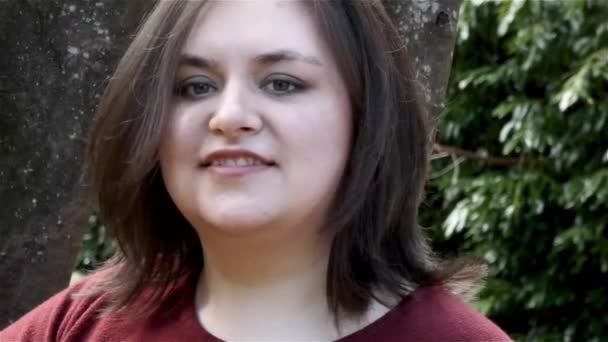 Young woman in red shirt standing near tree — Stock Video