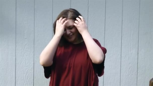 Молода жінка в червоному сміху біля будівлі — стокове відео