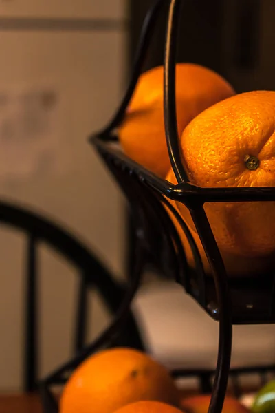 Naranjas apiladas en una cesta de alambre negro — Foto de Stock