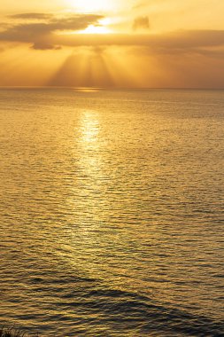 güneşin doğuşunda güneş ışınları ve bulutlar ile okyanus genişleri
