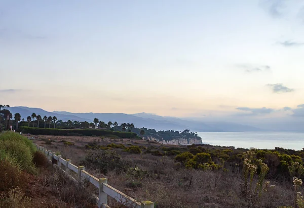 Sis ile okyanus manzarası ile uçurumun boyunca çit — Stok fotoğraf