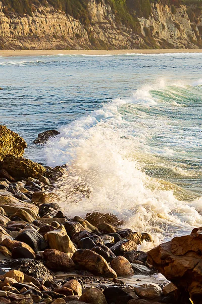 Ola rompiendo en las rocas en la costa con el amanecer —  Fotos de Stock