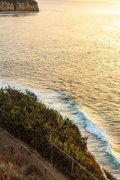 Вид со стороны скалы на океанскую волну, ломающуюся под траекторией — стоковое фото