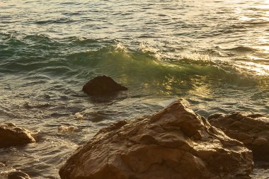 kayalara doğru hareket eden saydam yeşil ve sarı ışıkla oluşan kıvrılma dalgası