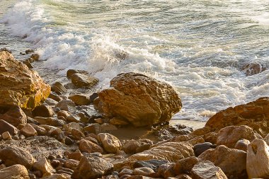 kayalık kıyı şeridi ile gün doğumunda köpüklü dalga kırma