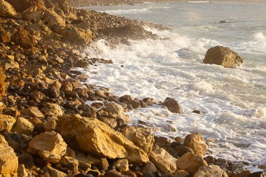 kayalık kıyı şeridi ile gün doğumunda köpüklü dalga kırma