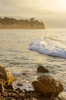 kayalık kıyı şeridi ile gün doğumunda köpüklü dalga kırma